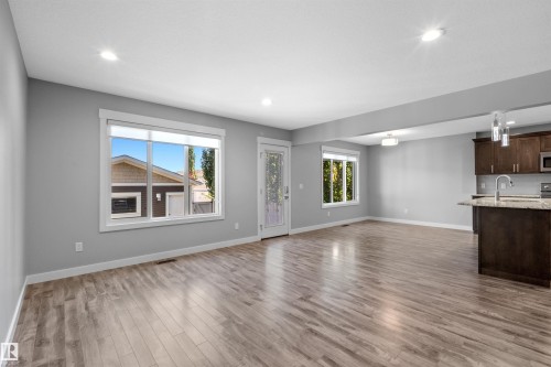 Open-concept living space with wood-finish flooring, recessed lighting, and large windows - 2585 Pegasus Boulevard Nw, Edmonton, AB 