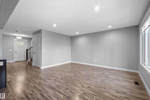 Spacious living area featuring wood-finish flooring, recessed lighting, and large windows - 2585 Pegasus Boulevard Nw, Edmonton, AB 
