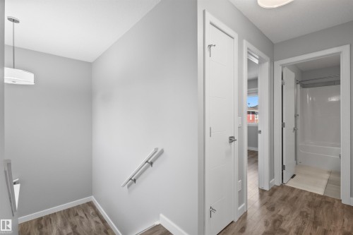 Wood-finish flooring, contemporary doors with horizontal accents, white trim, and a full bathroom with a shower-over-tub combination - 2585 Pegasus Boulevard Nw, Edmonton, AB 