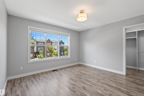 Wood-finish flooring, white trim, recessed closet with shelving, and a prominent window with a multi-pane design - 2585 Pegasus Boulevard Nw, Edmonton, AB 