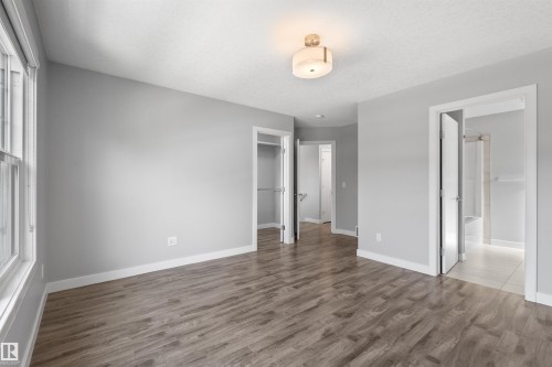 Wood-finish flooring, light gray wall color, white trim throughout, flush mount ceiling fixture, and a window with white casing - 2585 Pegasus Boulevard Nw, Edmonton, AB 