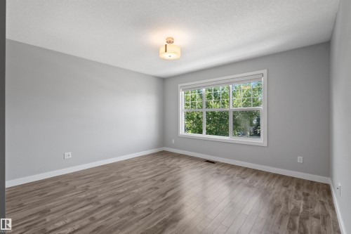 Room featuring wood-finish flooring, a large window, a ceiling-mounted light fixture, and light gray walls - 2585 Pegasus Boulevard Nw, Edmonton, AB 