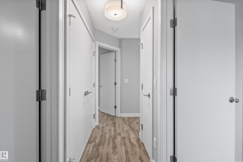 Hallway with wood-finish flooring, overhead flush-mount lighting, and light-toned walls - 2585 Pegasus Boulevard Nw, Edmonton, AB 
