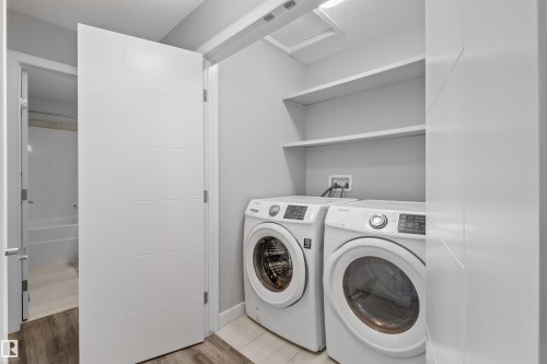 Laundry area featuring a stackable washer and dryer, integrated shelving, and tile flooring - 2585 Pegasus Boulevard Nw, Edmonton, AB 