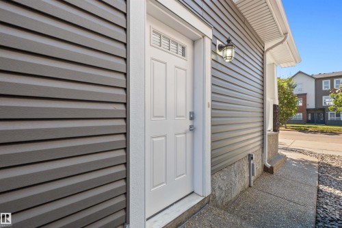 Exterior door with transom window, horizontal siding, and an exterior wall light - 2585 Pegasus Boulevard Nw, Edmonton, AB 