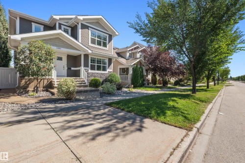 Two-story exterior with siding and stone accents, featuring a covered front porch and concrete walkway - 2585 Pegasus Boulevard Nw, Edmonton, AB 