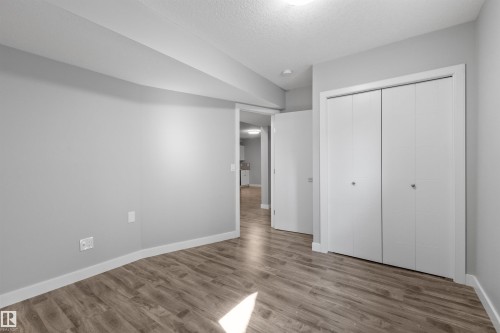 Neutral gray walls with wood-finish flooring, white trim, and a bi-fold closet - 2585 Pegasus Boulevard Nw, Edmonton, AB 