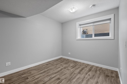 Wood-finish flooring, light grey walls, white trim, and a window with a window well - 2585 Pegasus Boulevard Nw, Edmonton, AB 
