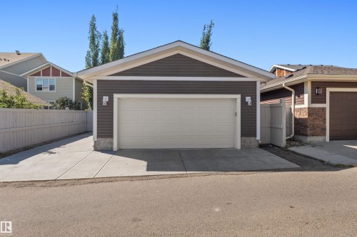 Detached garage with horizontal siding, a white garage door, and a concrete driveway - 2585 Pegasus Boulevard Nw, Edmonton, AB 