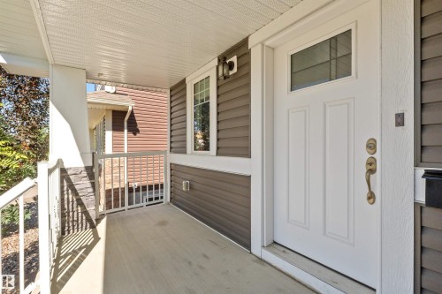 Covered porch with concrete flooring, white column, decorative stone paneling, and white railing - 2585 Pegasus Boulevard Nw, Edmonton, AB 