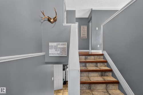 Staircase featuring tile treads, wood risers, and white trim accents - 131 Pine Drive, Wetaskiwin, AB - Indoor Photo Showing Other Room