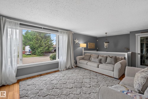 Spacious interior room featuring wood-finish flooring, a large picture window, and a decorative pendant light fixture - 131 Pine Drive, Wetaskiwin, AB - Indoor