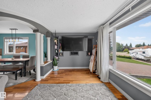 Spacious living area featuring wood-finish flooring, a large picture window, and a built-in media center - 131 Pine Drive, Wetaskiwin, AB - Indoor Photo Showing Other Room
