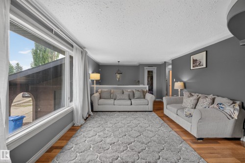 Living area featuring wood-finish flooring, a large picture window, and crown molding - 131 Pine Drive, Wetaskiwin, AB - Indoor Photo Showing Other Room