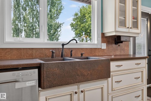 Kitchen featuring a hammered copper farmhouse sink, bronze-finish faucet, and coordinating hardware - 131 Pine Drive, Wetaskiwin, AB - Indoor Photo Showing Kitchen With Double Sink