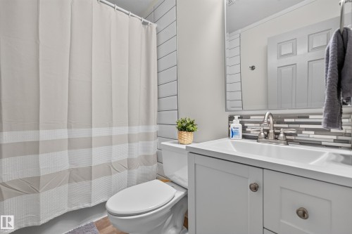 Bathroom featuring a white vanity with integrated sink, brushed nickel faucet, and a tiled backsplash - 131 Pine Drive, Wetaskiwin, AB - Indoor Photo Showing Bathroom