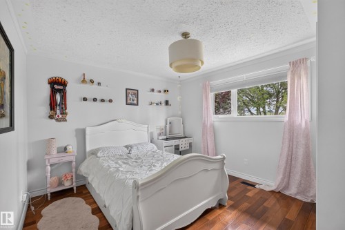 Wood-finish flooring accentuates this room featuring white walls and crown molding - 131 Pine Drive, Wetaskiwin, AB - Indoor Photo Showing Bedroom