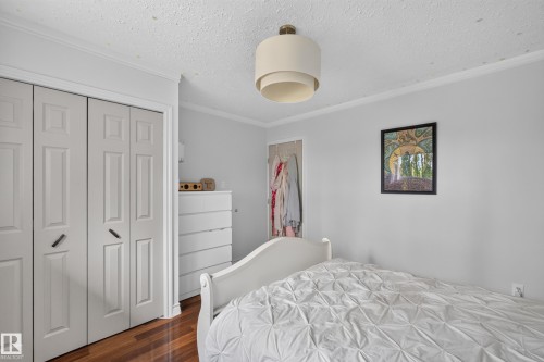 Interior room featuring wood-finish flooring, white bifold closet doors, light gray walls, a built-in closet, and a ceiling-mounted light fixture - 131 Pine Drive, Wetaskiwin, AB - Indoor Photo Showing Bedroom