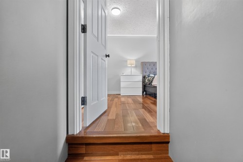 Bedroom featuring wood-finish flooring, a white paneled door with black hardware, and a ceiling-mounted light fixture - 131 Pine Drive, Wetaskiwin, AB - Indoor Photo Showing Other Room