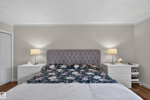 Neutral-toned bedroom featuring a tufted upholstered headboard, crown molding, and wood-finish flooring - 131 Pine Drive, Wetaskiwin, AB - Indoor Photo Showing Bedroom