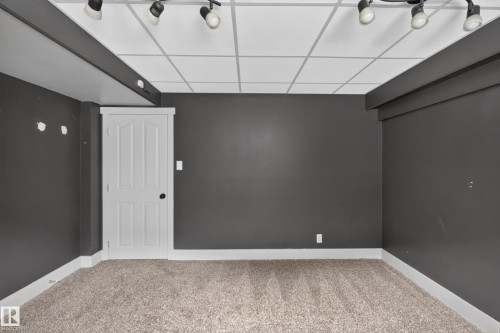 Carpeted room featuring dark gray walls and a drop ceiling with track lighting - 131 Pine Drive, Wetaskiwin, AB - Indoor Photo Showing Other Room