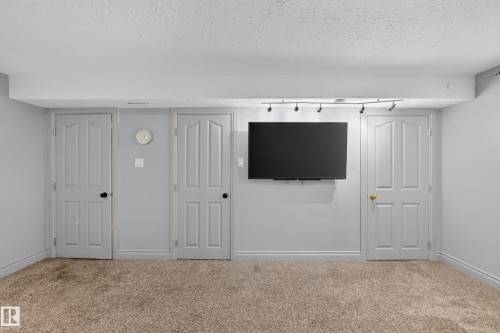Carpeted room featuring light gray walls, white trim, and a white ceiling with track lighting - 131 Pine Drive, Wetaskiwin, AB - Indoor Photo Showing Other Room