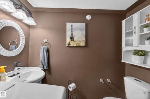 Pedestal sink with chrome fixtures and a round decorative mirror - 131 Pine Drive, Wetaskiwin, AB - Indoor Photo Showing Bathroom
