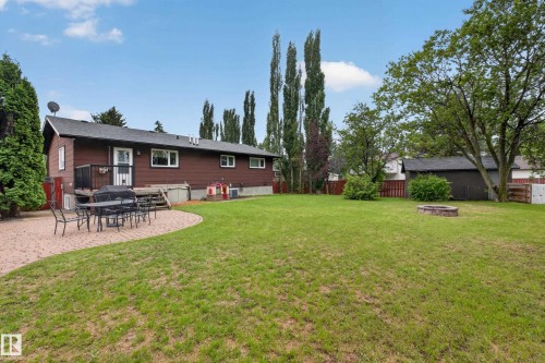 Expansive backyard featuring a manicured lawn, a large paver patio, and a built-in fire pit - 131 Pine Drive, Wetaskiwin, AB - Outdoor