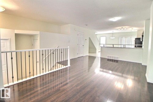 Dark wood-finish flooring throughout the main level - #18 4850 Terwillegar Cm Nw, Edmonton, AB 