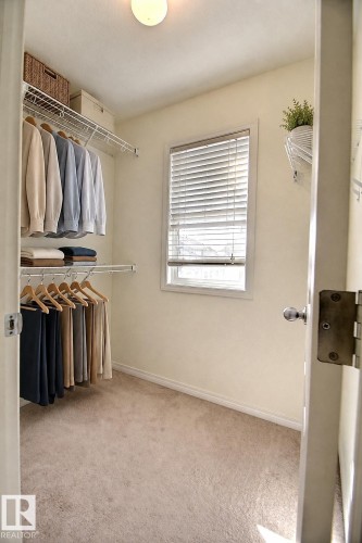 Built-in wire shelving system, neutral carpeting, window with privacy blinds, and flush-mount ceiling light - #18 4850 Terwillegar Cm Nw, Edmonton, AB 