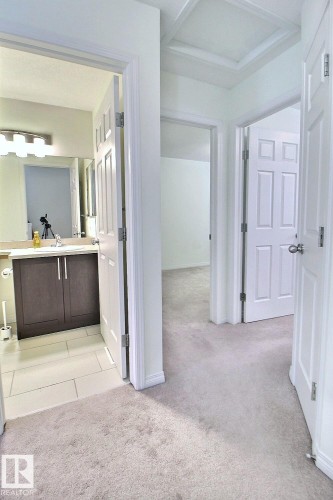 Hallway with light-toned carpeting and multiple paneled doors - #18 4850 Terwillegar Cm Nw, Edmonton, AB 
