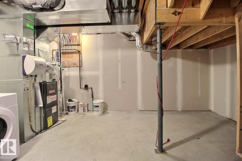 Unfinished basement space with a concrete floor, exposed ceiling joists, and a partial drywall finish - #18 4850 Terwillegar Cm Nw, Edmonton, AB 