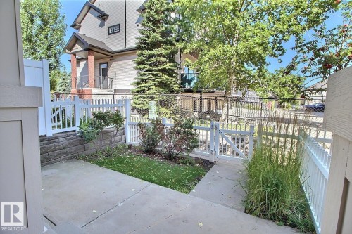Outdoor patio with concrete paving, white picket fencing, and landscaped garden beds - #18 4850 Terwillegar Cm Nw, Edmonton, AB 