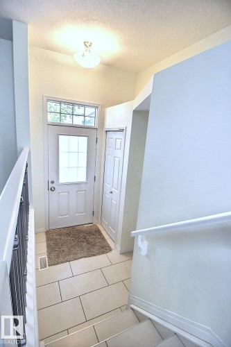 Entryway featuring a transom window, tile flooring, and a built-in closet with bifold doors - #18 4850 Terwillegar Cm Nw, Edmonton, AB 