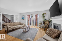 Light wood-finish flooring, white fireplace with tile surround, white trim, and a built-in staircase with wood railing - 