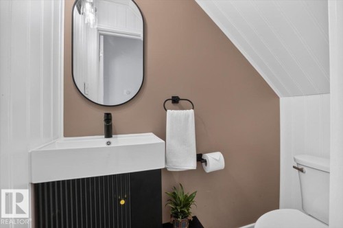 Modern powder room featuring a sleek black vanity with vertical ribbed detailing, white rectangular vessel sink, and matte black wall-mounted faucet - 17107 80 Avenue Nw, Edmonton, AB 