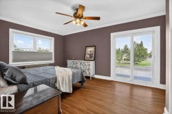 Wood-finish flooring, white crown molding, ceiling fan with integrated lighting, a double window, and a sliding glass door - 