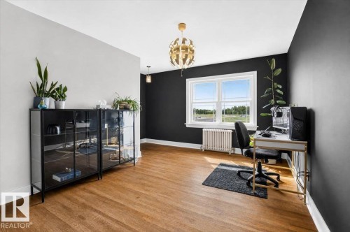 Hardwood flooring, white trim, gold-tone chandelier, white window frame, and a wall-mounted radiator - 17107 80 Avenue Nw, Edmonton, AB 