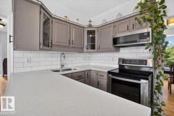 Kitchen featuring light gray cabinetry, white subway tile backsplash, light-toned countertops, and stainless steel appliances - 