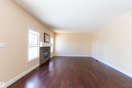 Hardwood flooring, stone-clad fireplace with white mantel, and multiple windows - 1419 Chahley Place Nw, Edmonton, AB 