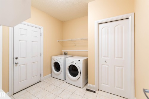 Utility room featuring tile flooring, white bi-fold doors, and a wire storage shelf - 1419 Chahley Place Nw, Edmonton, AB 