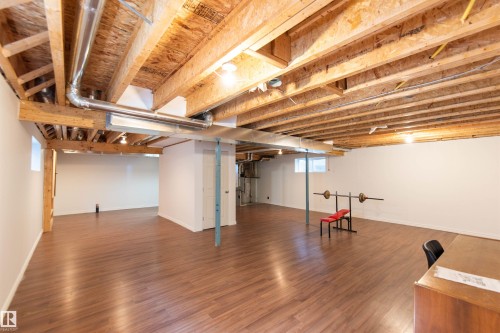 Spacious unfinished basement featuring exposed ceiling joists, wood-finish flooring, and white painted walls - 1419 Chahley Place Nw, Edmonton, AB 