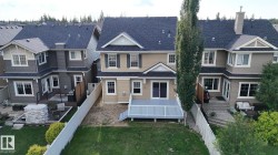 Two-story residence with a light beige siding, a dark shingle roof, and white window trim - 