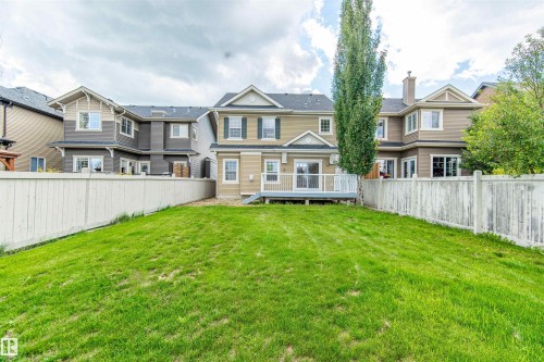 Expansive backyard with a manicured lawn, a full-width wooden deck, and a privacy fence - 1419 Chahley Place Nw, Edmonton, AB 