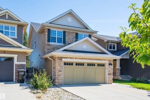Two-story residence featuring a stone and siding exterior, front-facing attached garage, and a concrete driveway - 1419 Chahley Place Nw, Edmonton, AB 