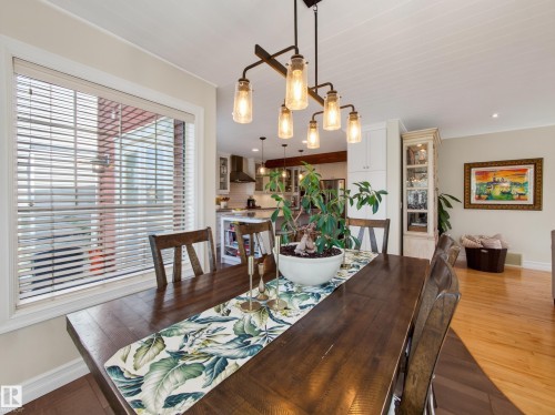Dining area with wood-finish flooring, a rectangular window with blinds, and a multi-bulb linear chandelier - 1223 Appleton Close, Sherwood Park, AB 