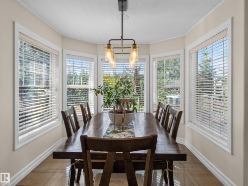 Bay window with white trim, wood-finish flooring, and a linear chandelier with glass shades - 1223 Appleton Close, Sherwood Park, AB 