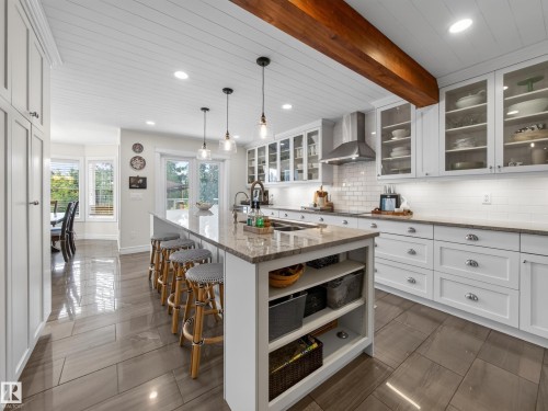 Gourmet kitchen featuring a large central island, white shaker cabinetry, stainless steel appliances, and wood-finish ceiling beams - 1223 Appleton Close, Sherwood Park, AB 