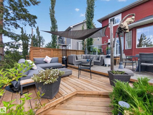 Multi-level wood deck featuring a shade sail and glass panel railing - 1223 Appleton Close, Sherwood Park, AB 