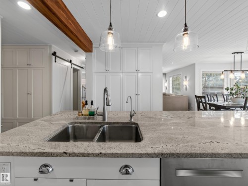 Kitchen island featuring a double basin stainless steel sink, a gooseneck faucet, and light-toned countertops - 1223 Appleton Close, Sherwood Park, AB 